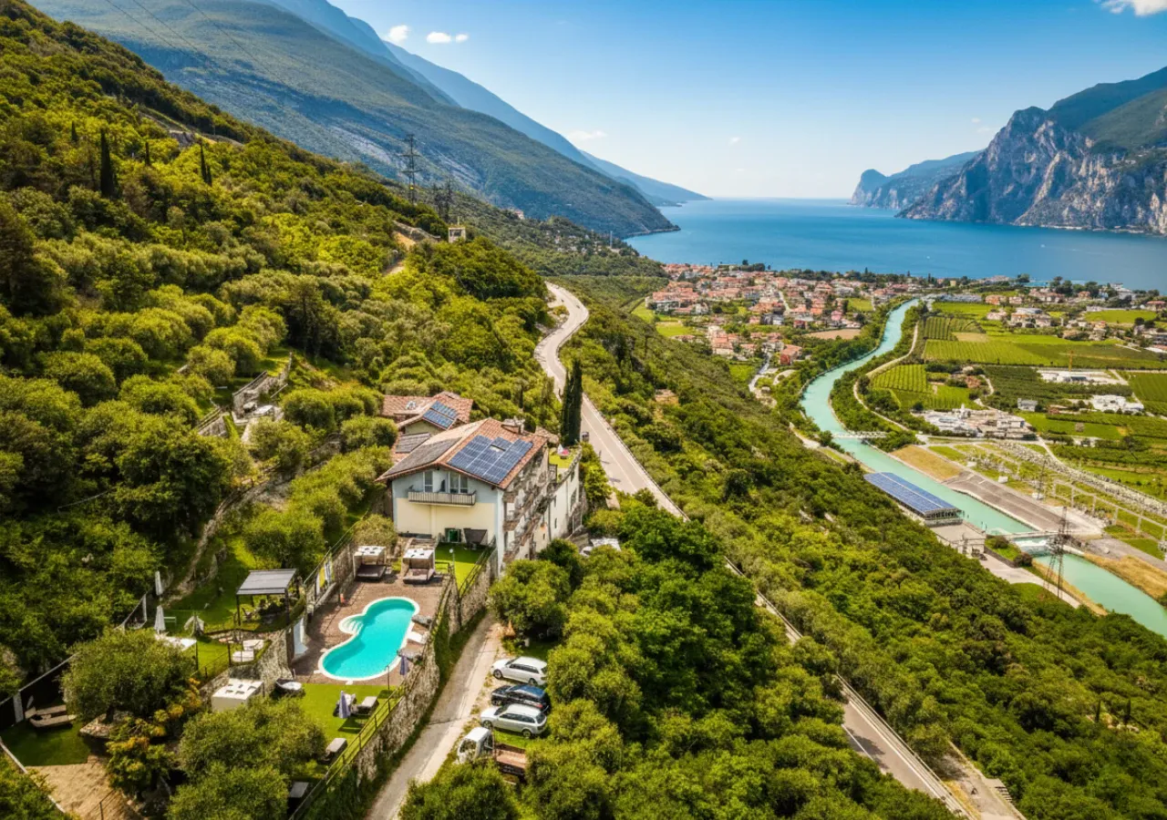 L'hotel con il tetto fotovoltaico e la piscina dall'alto, sotto il lago con Riva e il monte Brione